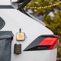Luno Magnetic Can Cooler attached to SUV exterior while vehicle camping